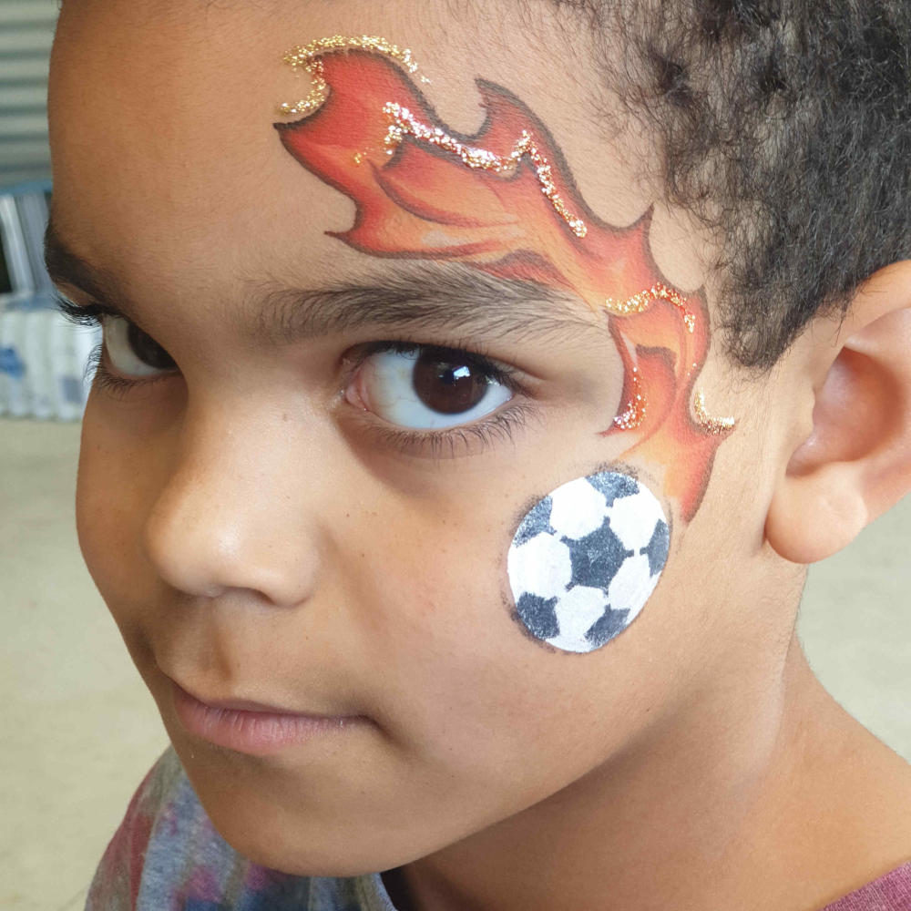 Young boy with flaming soccer ball face paint.